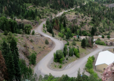 looking down on a curved dirt road in a small, forested town